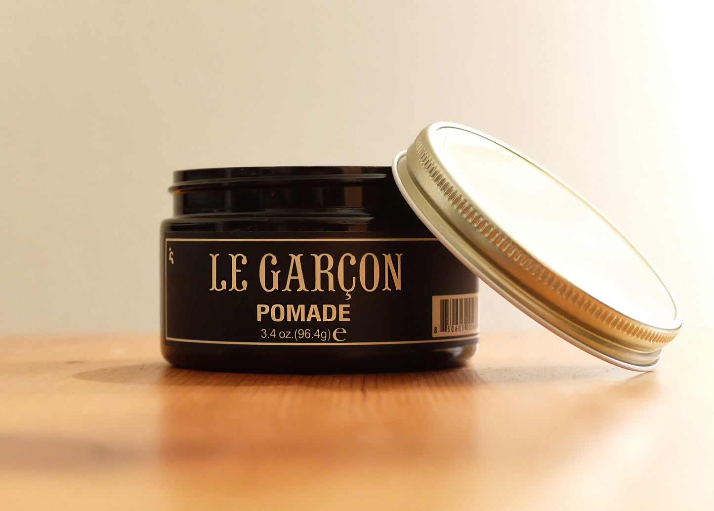 Open jar of Le Garçon Hair Styling Pomade on a wooden surface, premium men's hair product